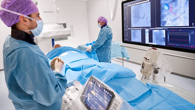 An interventional radiologist performing a procedure using a C-arm for guidance.