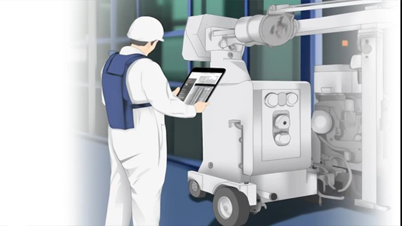 A technologist standing at a distance and holding the exposure button for a portable X-ray.