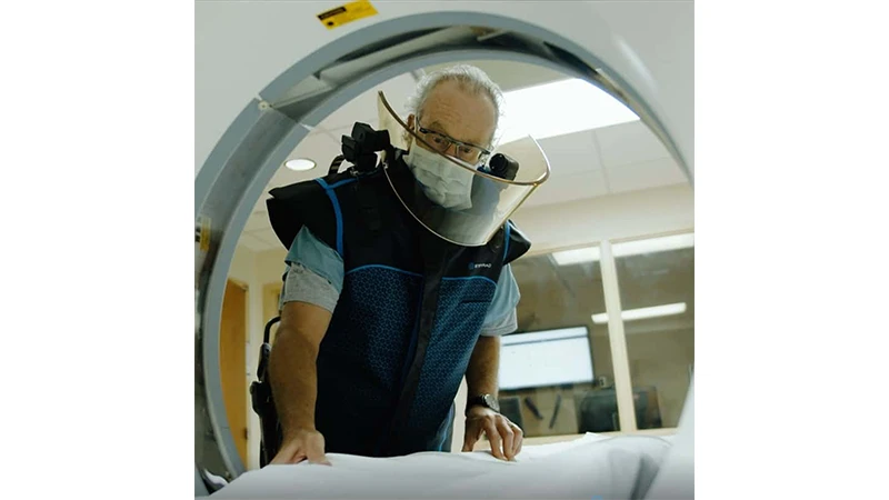 A photo of a radiology technologist wearing a lead apron and a thyroid shield.