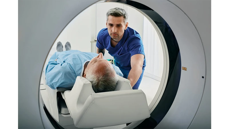A friendly technologist explaining a procedure to a patient next to a CT scanner.